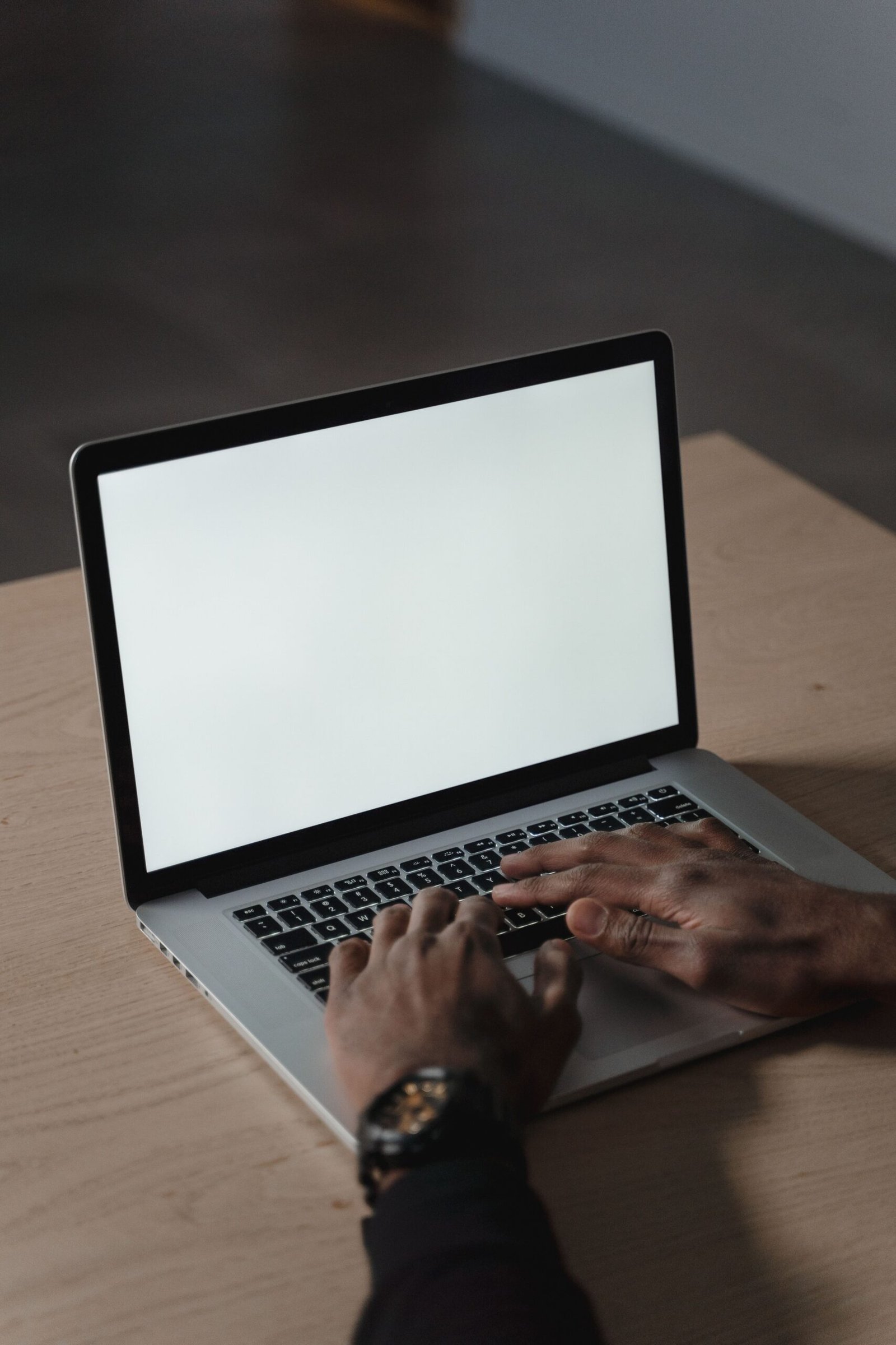 Close-up of hands typing on a blank screen laptop, creating a versatile workspace image.
